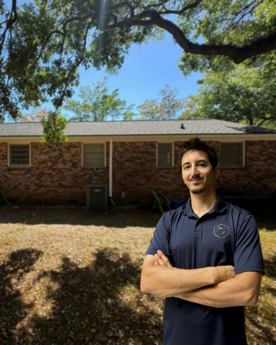 Alec, owner of Seaside Comfort Solutions, in the backyard of a Charleston home with the condenser he relocated behind him